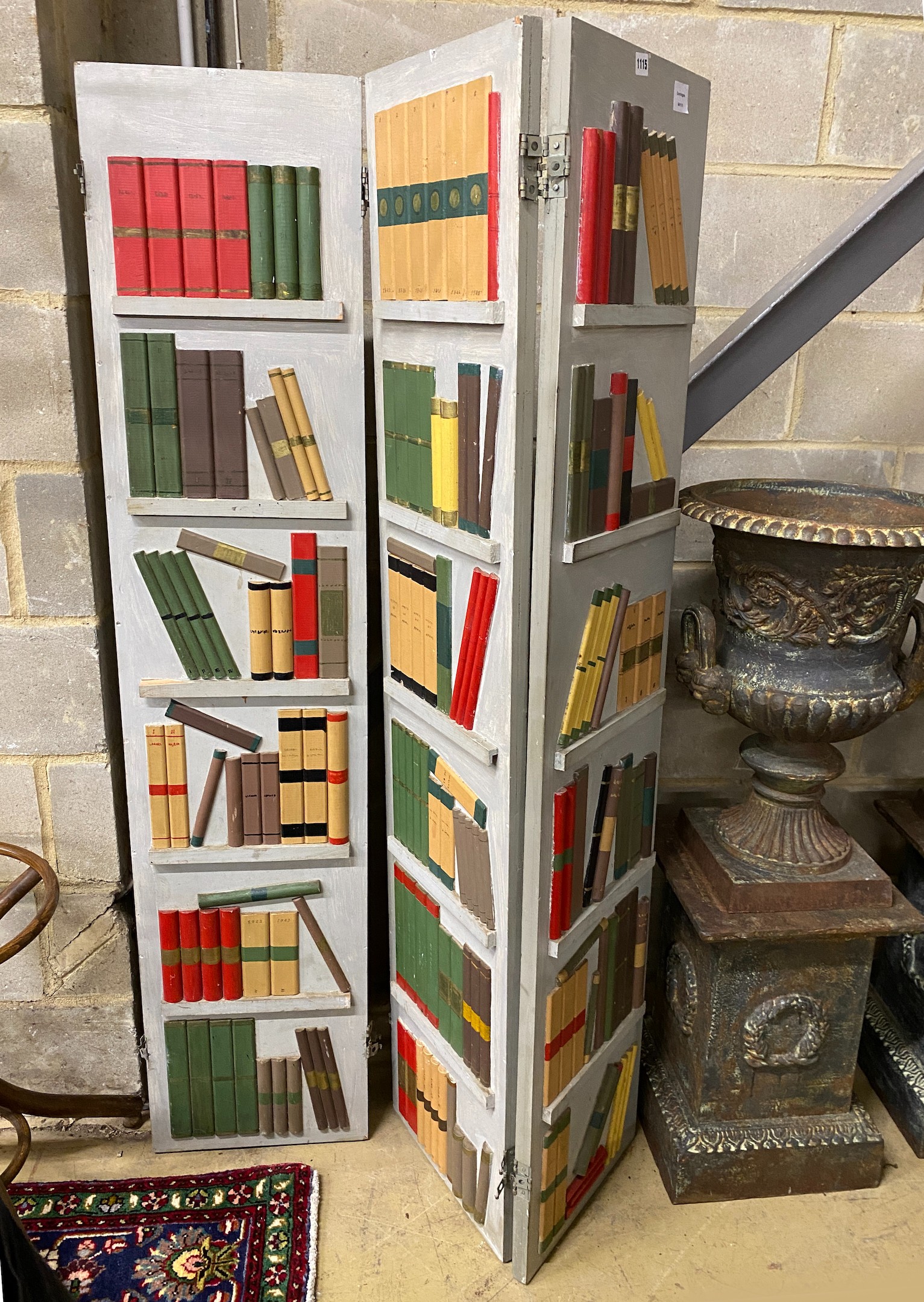 A painted wood three fold dressing screen modelled as a bookcase by Georges Liotard, each panel width 36cm, height 165cm